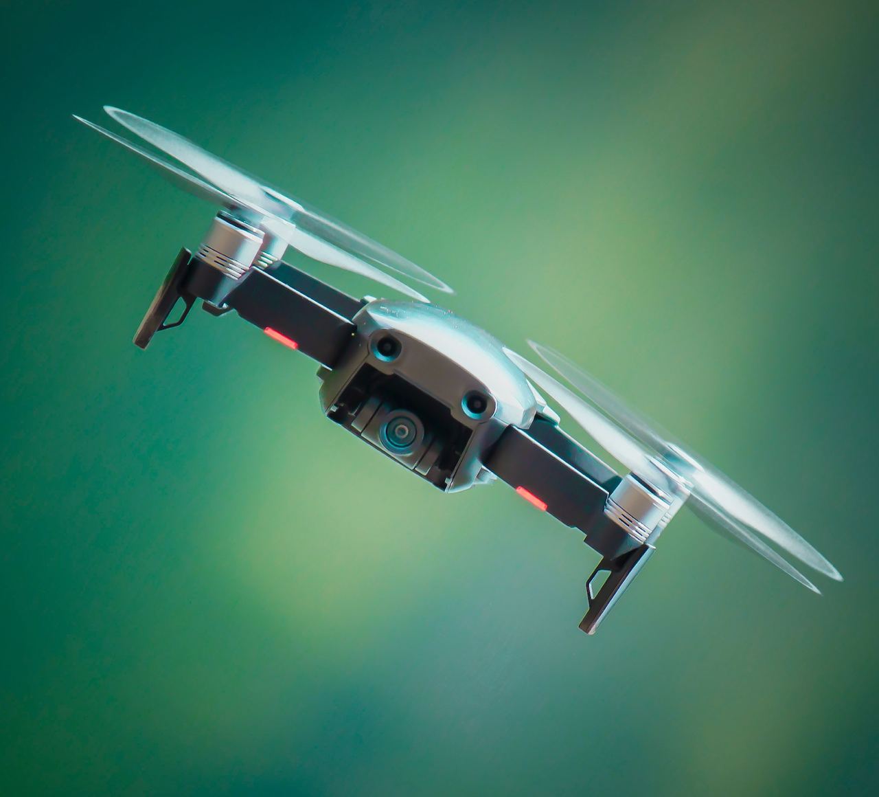 An action image of a dark grey drone heading towards the camera. The green background is blurred.
